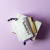 bohokiwi bamboo cleaning brush with cotton storage bags on a purple background