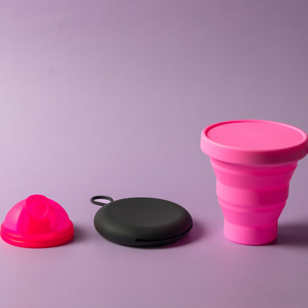 Bohokiwi Neon Pink menstrual disc with Black round carrier case and Hot Pink collapsible steriliser